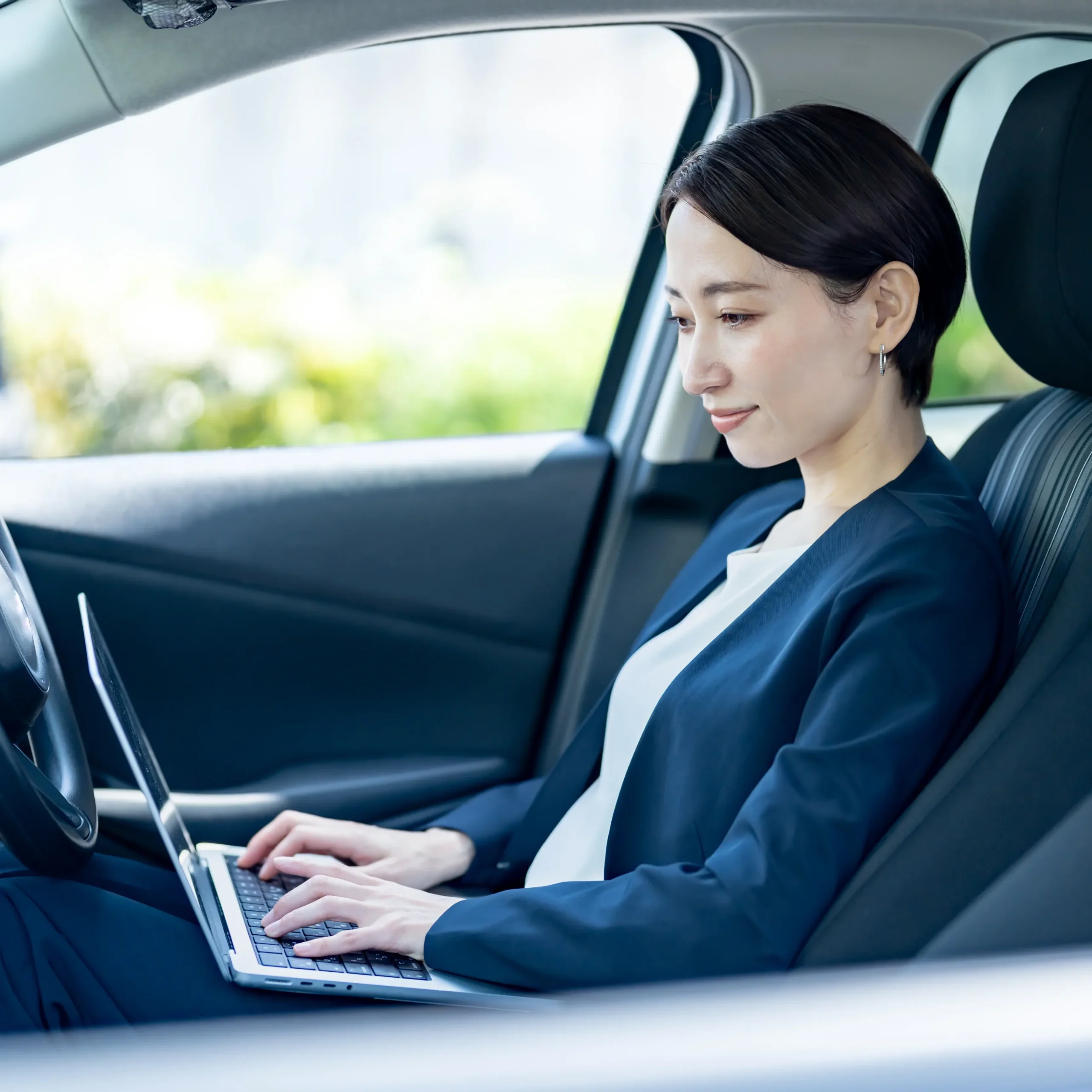車内でパソコンを使って学習する女性